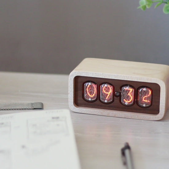 Clock sits on counter table made from solid maplewith a contrasting walnut face. The design uses retro Nixie tubes for a warm orange glow.