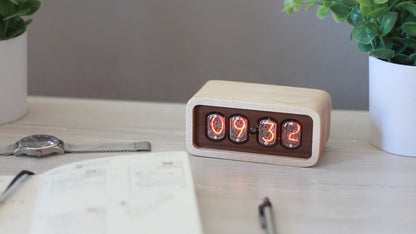 Clock sits on counter table made from solid maplewith a contrasting walnut face. The design uses retro Nixie tubes for a warm orange glow.