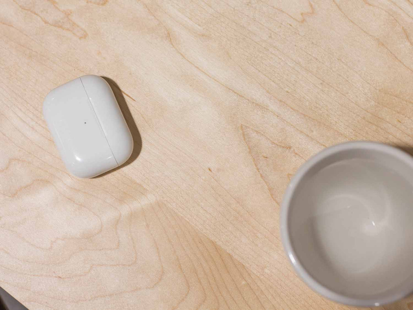 A side table placed in a living room with a plant and coffee mug sat on the table top. The side table is made from light maple hardwood and is crafted in Scandinavian minimalist modern design.